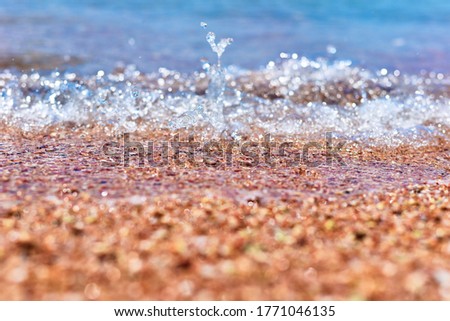 Sea wave on the sand beach, soft focus. Summer background. Waves with splashes and foam. 