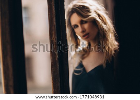 Defocused art portrait of a beautiful blonde woman with smoky eyes with make-up through the glass in beige tinting. Out of focus