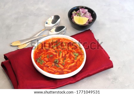 Traditional Sev bhaji or sev tamatar nu Shaak. its a sweet & spicy tomato curry topped with sev. Sev is a crisp fried gram flour vermicelli. Served with chopped onion and lemon. with Copy space. Royalty-Free Stock Photo #1771049531