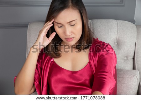 Have a Headache and stress, Women in red nightgown & satin robe dizzy until insomnia on the white bed at Living room. Royalty-Free Stock Photo #1771078088