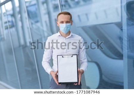 A man in a medical mask shows a tablet with a message. Large plan. Place for text.