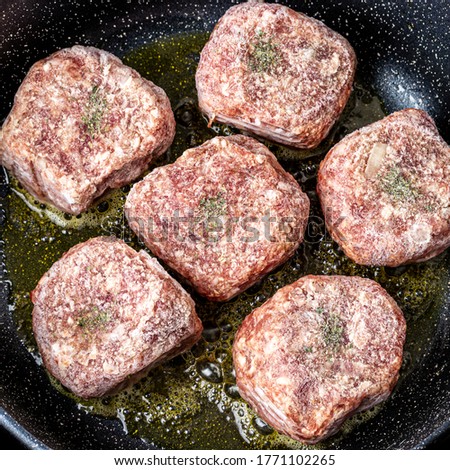 Raw beef cutlets, heated in a ceramic black skillet with vegetable oil. The process of frying steaks. Traditional cuisine.