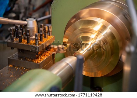 The operation of lathe machine cutting the brass shaft parts with the cutting tools. The metalworking process by turning machine.