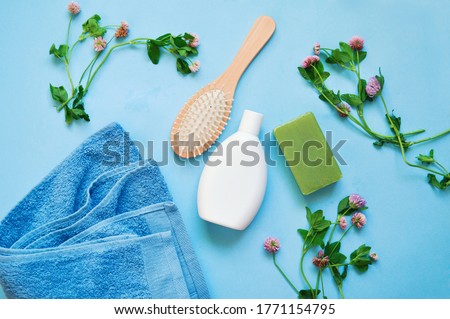 Natural organic cosmetic for hair and body care. Herbal bath products. Moisturizing shampoo, soap bar, wooden hair brush, towel and clover
