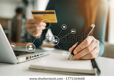 Women use credit cards to pay through laptop computer and take notes in office.