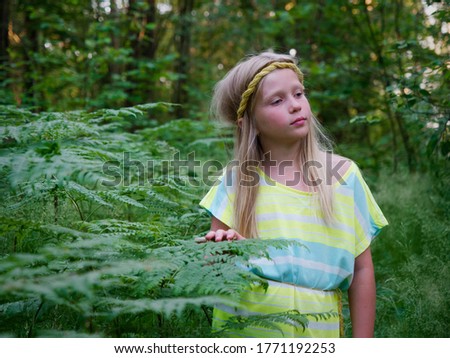 portrait of a blonde girl with blue eyes in green thickets