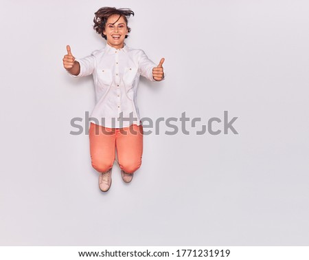Young beautiful woman wearing casual clothes smiling happy. Jumping with smile on face doig ok sign with thumbs up over isolated white background.