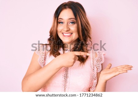 Young beautiful caucasian woman wearing casual clothes amazed and smiling to the camera while presenting with hand and pointing with finger. 