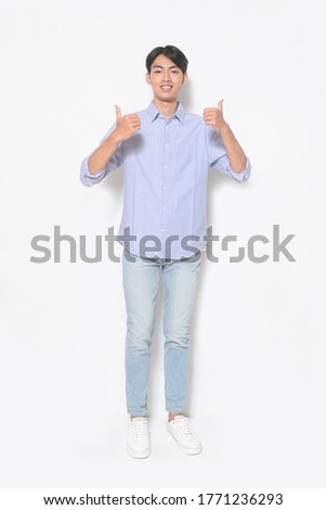 full length handsome casual man wearing striped long sleeved shirt with blue jeans, white sneaker making two thumbs up sign