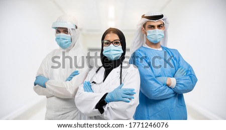 Successful team of Arabic medical doctors are looking at camera while standing in hospital with arms crossed male and female doctors in protective gear fighting coronavirus COVID-19. Royalty-Free Stock Photo #1771246076