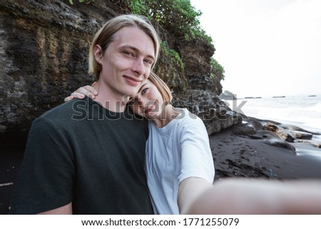 Young couple enjoy a trip together on the beach take a photo together