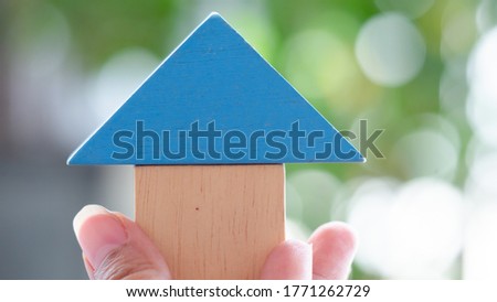 Hand holding pieces wooden model stacked as a house, Concept Having a house or buying a home or home loan.