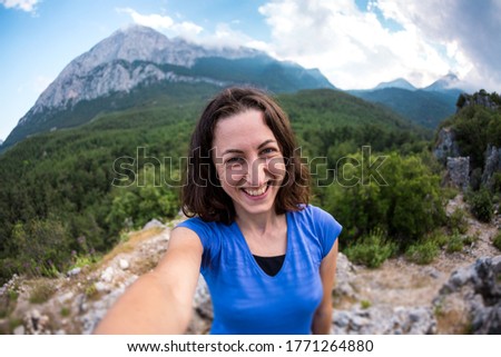 A woman takes a selfie on top of a mountain, a girl is photographed against a background of a mountain valley, a trip to the picturesque places of Turkey.