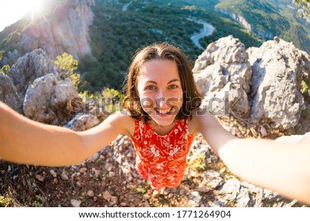 A woman takes a selfie on top of a mountain, a girl is photographed against a background of a mountain valley, a trip to the picturesque places of Turkey.