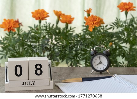 July 08, date on the calendar. Handmade wood cube with date month and day. flowers and clocks are in the background. selective focus. planning for the day.  the day of family, love and fidelity