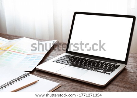 Workplace with laptop, notebook, and color samples on the wooden desk