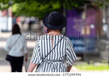 woman in striped clothes and with a black hat on a city street, rear view, selective focus