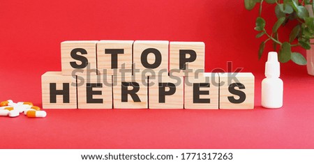 The words STOP HERPES is made of wooden cubes on a red background with medical drugs. Medical concept.