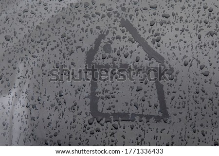 House drawn with a finger on the wet glass with drops.