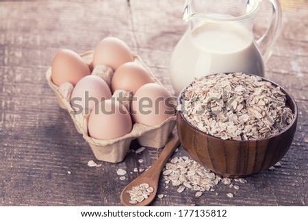 Ingredients for baking  -  oat flakes, eggs, milk on  wooden background. Retro style,toned image. Selective focus.