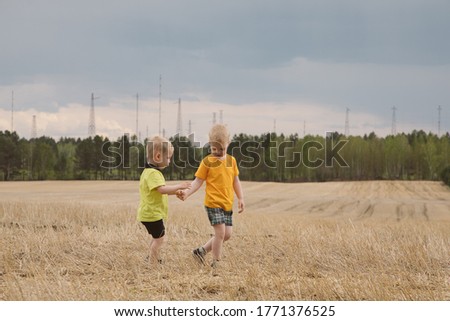 two brothers walk in a mown field