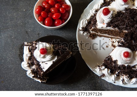 Black forest cake and cherries on a background with use of selective focus and rest of the portion, ingredients, piece and background blurred.