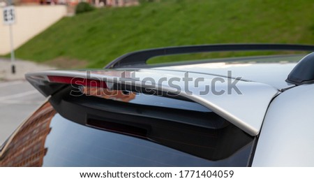Close-up on the trunk lid of a gray car with a plastic spoiler over the rear window to improve the aerodynamics of the car body during tuning for racing. Royalty-Free Stock Photo #1771404059