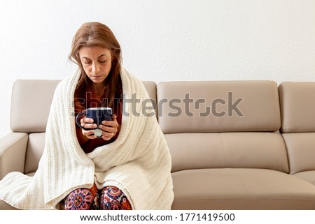 Sick woman on couch drinking tea