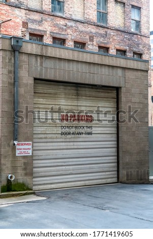 Corrugated metal garage door of an old brick building with No Parking sign