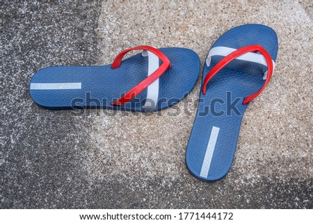A pair of red white and blue flip-flops left on the cement patio by the poolside on a hot summer day in July