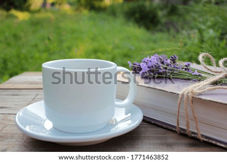 Cup of coffee and old book decorated with lavender flowers and tied with jute twine on wooden table. Copy space. Selective focus. Enjoying summer life
