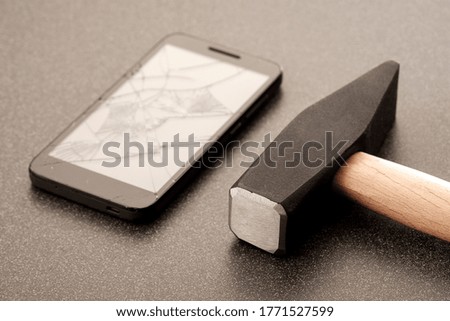 hammer broken mobile phone on a dark ceramic surface. broke the phone so you wouldn be disturbed