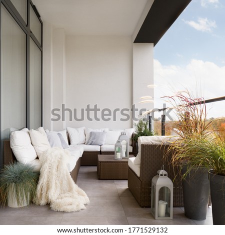 Stylish decorated balcony with rattan outdoor furniture, bright pillows, fluffy blanket and plants Royalty-Free Stock Photo #1771529132