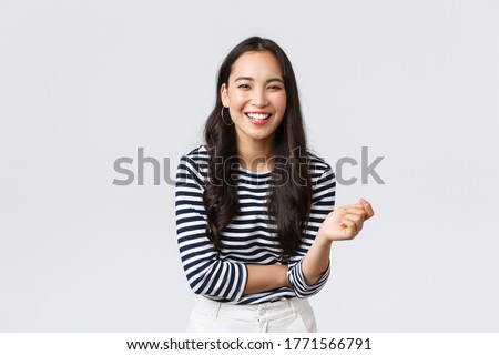 Lifestyle, people emotions and casual concept. Carefree happy outgoing asian woman having fun talking to people, laughing and smiling upbeat, standing white background cheerful