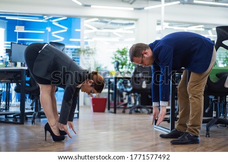 Colleagues play sports during the break. Health care concept at work. Middle managers in business suits doing fitness exercises in an open space office. Change of activity is the best rest.