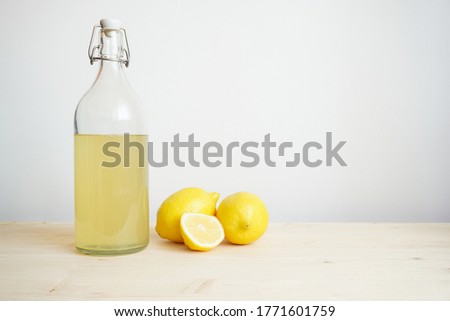 Lemonade in glass and bottle on wooden table. Lemonade or mojito cocktail with lemon and mint, cold refreshing drink or beverage with ice. Copy space for your text