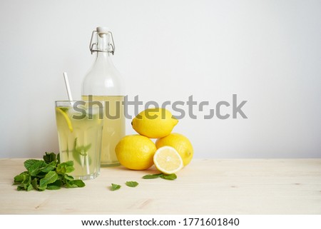 Lemonade in glass and bottle on wooden table. Lemonade or mojito cocktail with lemon and mint, cold refreshing drink or beverage with ice. Copy space for your text Royalty-Free Stock Photo #1771601840