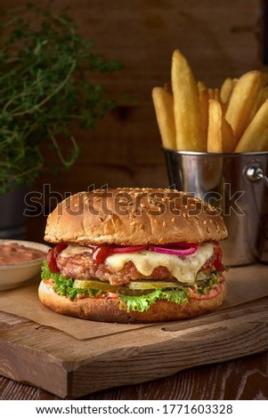 Fast food dish. Appetizing meat burgers, potato chips and vegetable. Takeaway composition. French fries, hamburger and sauces on wooden board