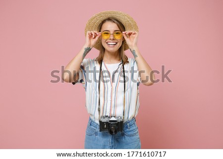 Cheerful traveler tourist young girl in striped shirt glasses hat with photo camera isolated on pink background. Passenger traveling abroad to travel on weekends getaway. Air flight journey concept