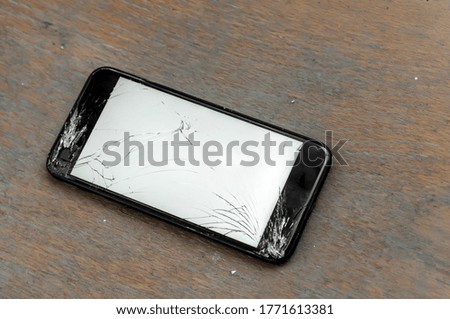 View on a cracked screen of a smartphone on a wooden surface.
