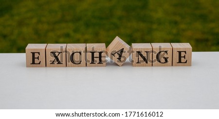 EXCHANGE word made with building blocks on white and green background.