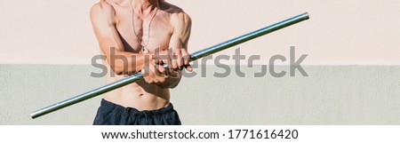 A middle aged man exercises with a metal pole