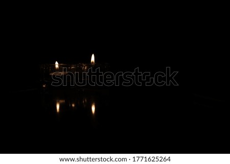 two candles burning on a black background