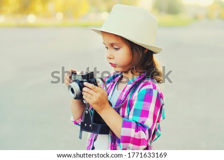 Close up child with retro camera taking picture wearing a summer straw hat outdoors