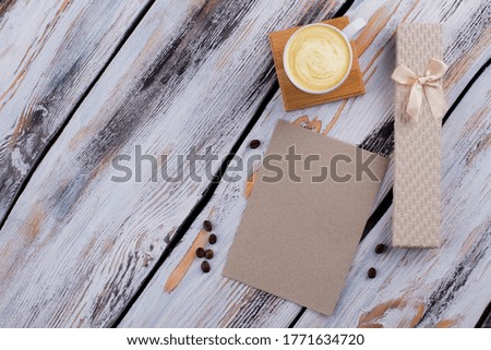 Flat lay morning paper with cup of coffee and gift box. Present for birthday or anniversary. White wooden background.