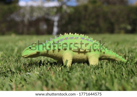 green toy dinosaur on the grass