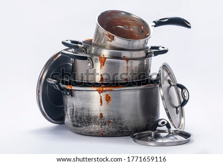 

Dirty pots and lids stacked together on a white background. Royalty-Free Stock Photo #1771659116