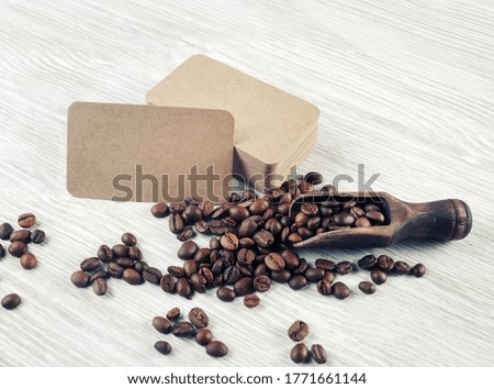 Blank kraft business cards and coffee beans on light wood table background.