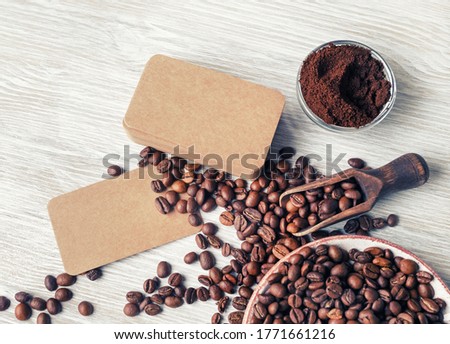 Photo of blank vintage business cards, coffee beans and ground powder on light wood table background. Flat lay.