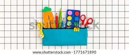 Pencil case with school supplies on grid background. Back to school concept banner.